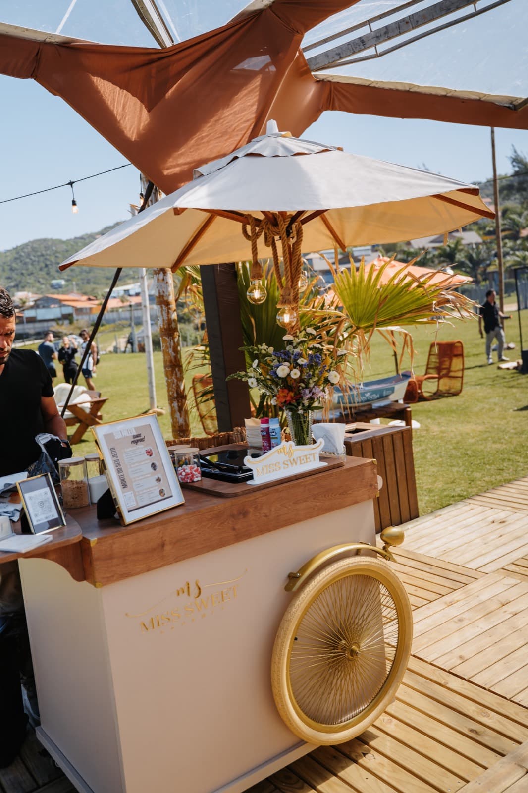 Carrinho de bar montado no deck, com guarda-sol e vista pro campo