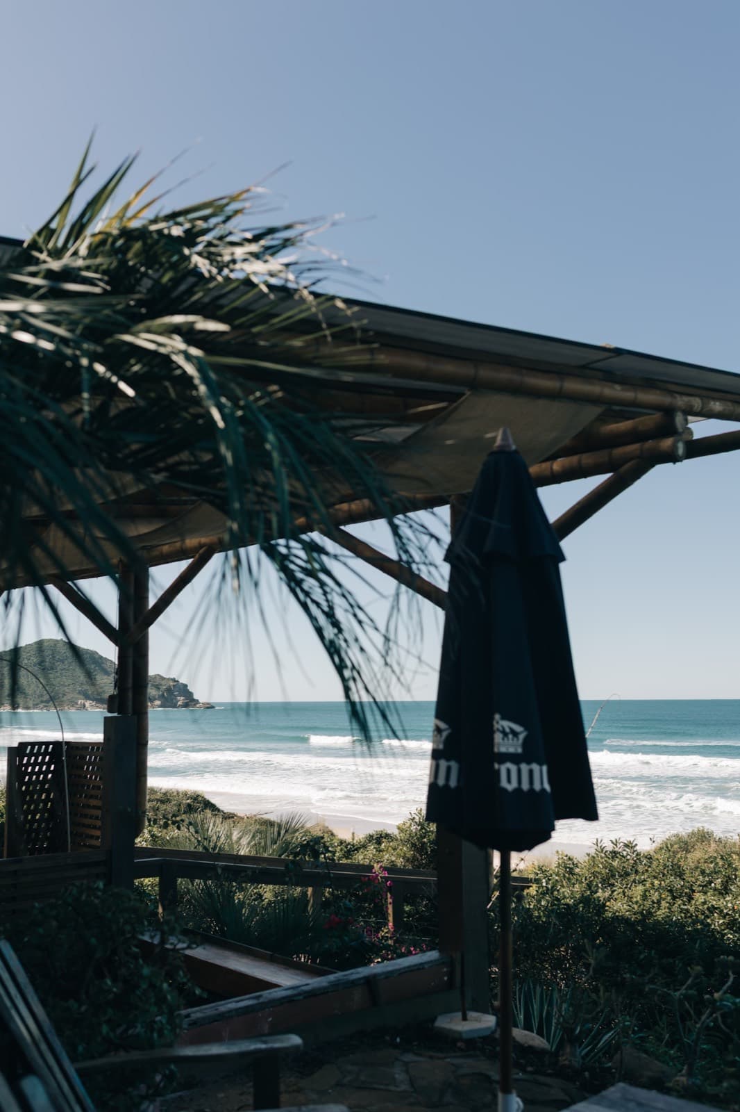 Deck do restaurante à beira-mar, com coqueiro e a praia ao fundo