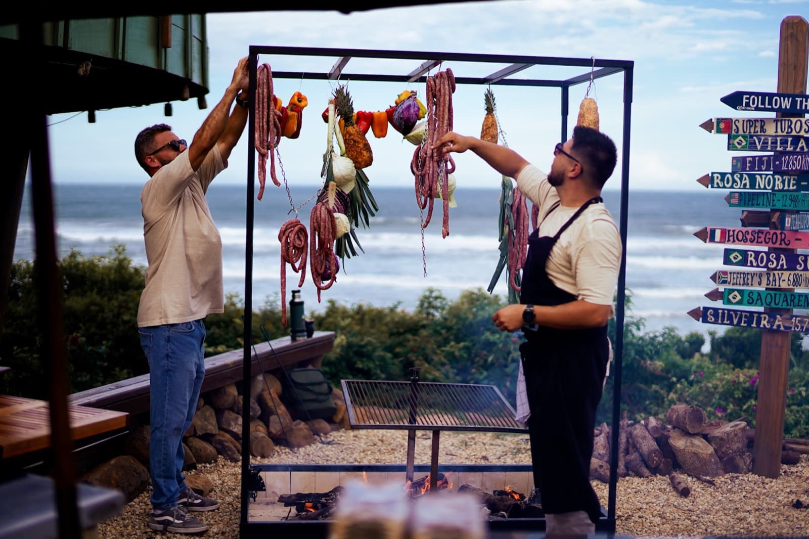 Equipe montando a ilha de parrilla à beira-mar, com frutos do mar pendurados na estrutura